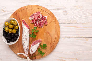 Salami and bread on white wooden background. Top view.