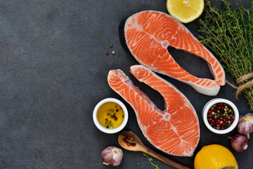 Raw salmon fish with spices on black. Top view.