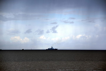 warship floats on the horizon in the rain dark cloud