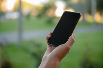 Closeup of female hands holding smart phone on outdoors background. Top side overhead view of mockup display nature backdrop, modern digital device mobil communication technology connection.