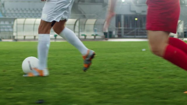 Focus on Legs of a Professional Soccer Player Leading with a Ball, Masterfully Dribbling Around His Opponents. Two Professional Football Teams Playing on Stadium. Low Angle Ground Shot.