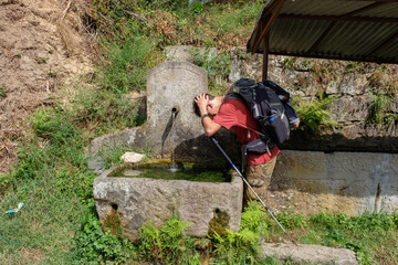 Pilger erfrischt sich an einem Brunnen auf dem Jakobsweg (von Porto nach Santiago de Compostela)