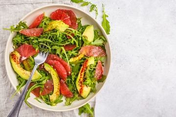 Avocado and grapefruit salad in a white plate on a white background.