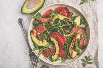 Avocado and grapefruit salad in a white plate on a white background.