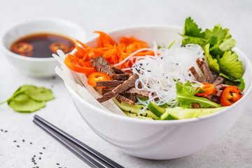 Bun cha salad bowl. Vietnamese rice noodle with beef and chilli vegetables salad in white bowl.
