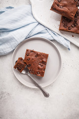 Piece of chocolate vegan cake with chocolate drops and nuts, top view.