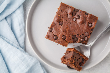 Piece of chocolate vegan cake with chocolate drops and nuts, top view.