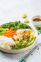 Vietnamese rice noodle with grilled tofu and  chilli vegetables salad in white bowl, copy space.