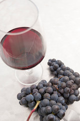 Cup of red wine and a cluster of grapes, vertical photo