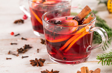 Christmas hot mulled wine with spices on wooden background.