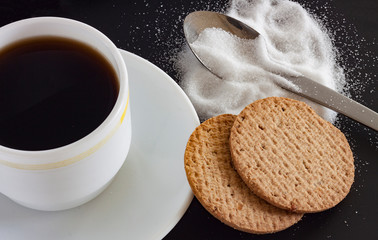 TAZA DE CAFÉ Y GALLETAS CON AZÚCAR SOBRE FONDO NEGRO