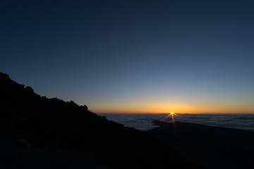 View from volcano Pico del Teide in Tenerife, right at sunrise time with a glowing sea of clouds reaching to the horizon