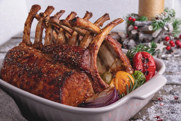 Grilled roasted rack of lamb chops with vegetables in ceramic baking dish. New Year christmas composition,decoration.