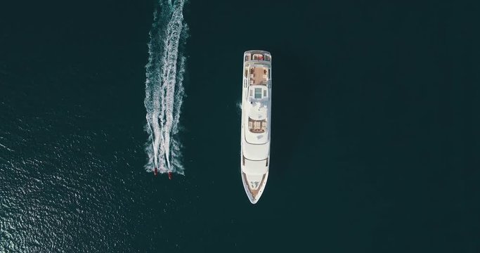 Top-down view of two jet-ski moving parallel to the large yacht
