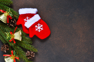 Christmas tree with decorations and mittens on a brown background with space under the text.