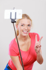 Woman taking picture of herself, phone on stick