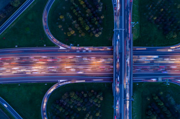 Highway junction seen from above at night with light trails of passing cars