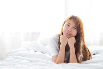 Beautiful portrait young asian woman lying and smile while wake up with sunrise at morning, lifestyle and relax concept.