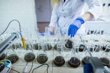 Hands of the scientist in laboratory shake a glass flasks with dissolved samples of the soil. Agrochemical examination of soil to more efficient use resources and optimize the use of fertilizers.