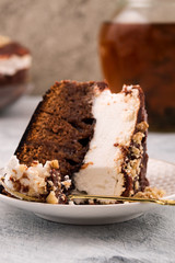Sliced chocolate cake on a plate. Vertical. Brown and white layer. Pitcher of drink.