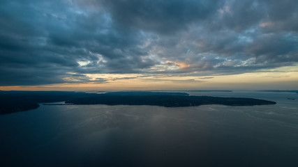 A colorful high aerial view of sunset over a Pacific Northwest island with dynamic clouds