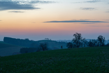 Jagdhochstand in Hügellandschaft bei Sonnenuntergang