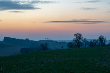 Fototapeta na wymiar Jagdhochstand in Hügellandschaft bei Sonnenuntergang