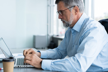 Senior businessman working on laptop computer in the office.