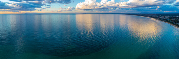 Mornington Peninsula coastline and Port Phillip Bay at sunset with beautiful cloud reflections - wide aerial panorama