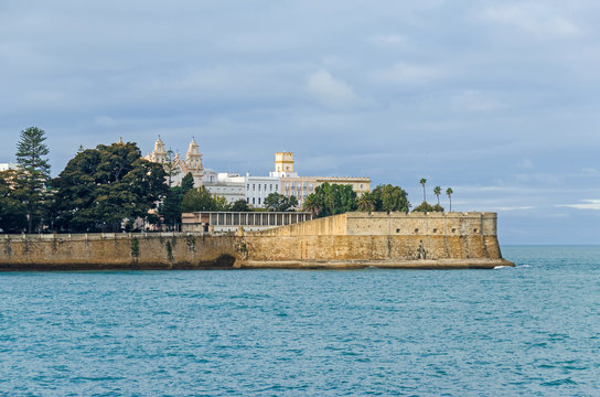City walls with the bastion Baluarte de la Candelaria and the park of Alameda Apodaca in the Old Town of Cadiz, Spain