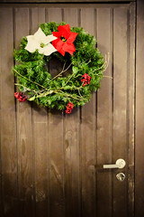 Christmas wreath on brown door with handle