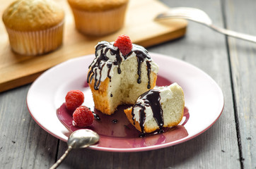 Muffin with cream and chocolate syrup. Cupcake with fresh raspberry berries. Cakes on the table. 