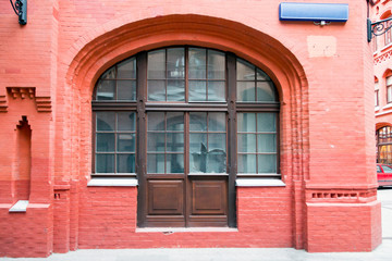 Facade of an old red brick building, arch, window with broken glass