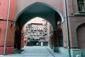 Arch of the european building of red brick with a wall with air conditioners in the background in Moscow, Russia