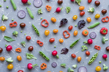 Clean eating concept. Fresh organic vegetables. Radish, green peas, broccoli, tomato and onion on grey background. 