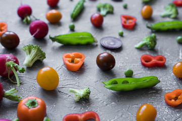 Fresh organic vegetables close up. Radish, green peas, broccoli, tomato and onion on grey background. 