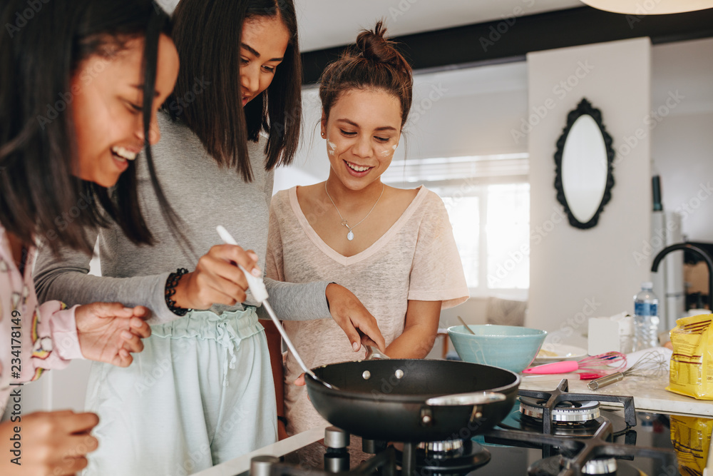 Wall mural teenage girls trying their hand at cooking