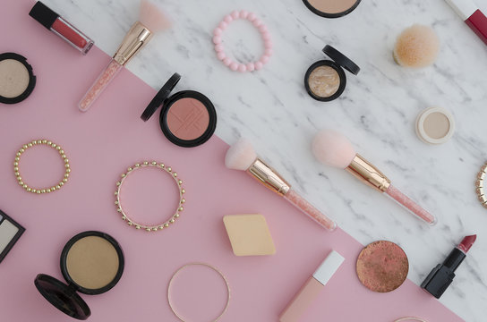 Flat lay Cosmetics for makeup, eye shadow, brush, highlighter, concealer, makeup, lipstick, mascara, blush marble and pink two colour vibrant duotone background.