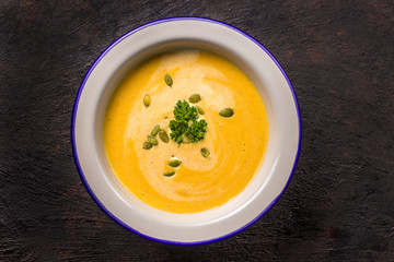 Seasonal autumn food - Spicy pumpkin soup with cream and pumpkin seeds.