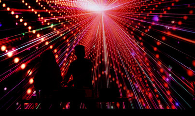 Boy and girl DJ silhouette on color laser light background.