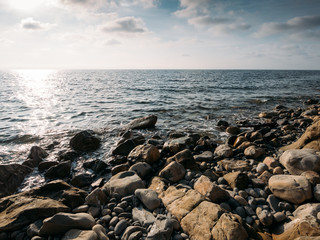 Stone beach at sea shore, close up. Ocean water waves at sunset, relaxation and tranquil nature background