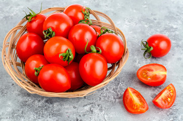 Small red ripe tomatoes in wicker wooden bowl