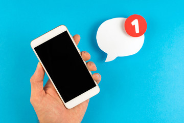 smartphone in the hand with one new message icon chat bubble, blue background.