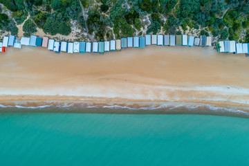 Looking down at scenic beach huts sand and turquoise ocean water - aerial view