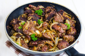 Frying pan with fried chicken giblets. Studio Photo