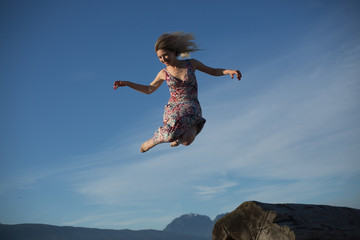 Conceptual positive mindset young woman jumping blue sky