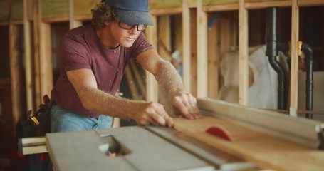 Carpenter expertly runs plywood through table saw