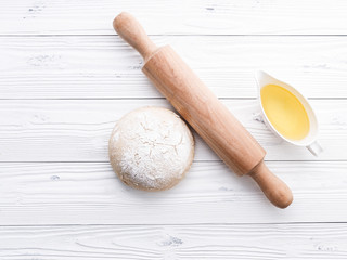 Raw pizza dough and rolling pin on wooden background