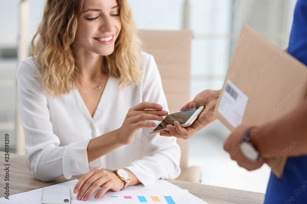 Poster Woman using smartphone app to confirm receipt of envelope from courier in office