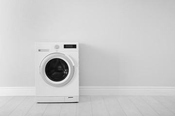 Washing machine near white wall, space for text. Laundry day